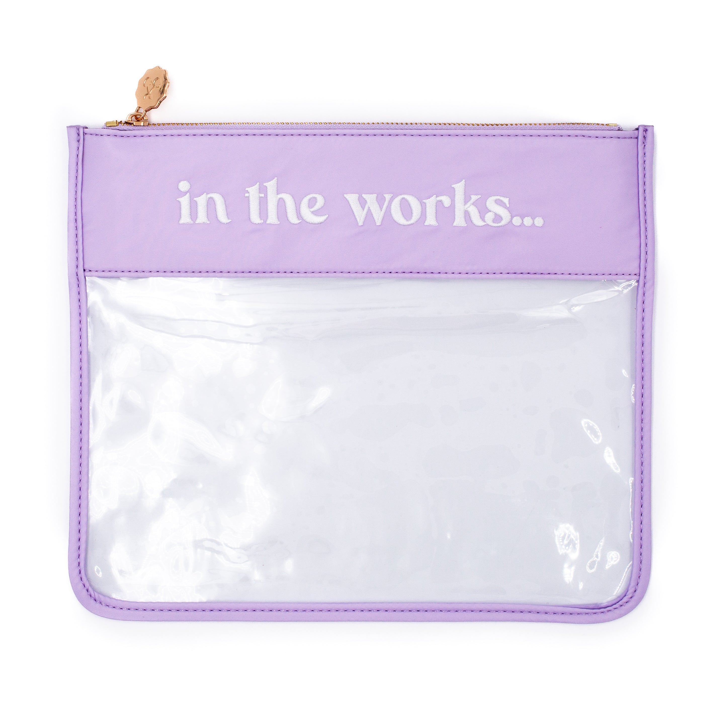 A lavender purple zippered pouch with a clear plastic front window and the words 'in the works.