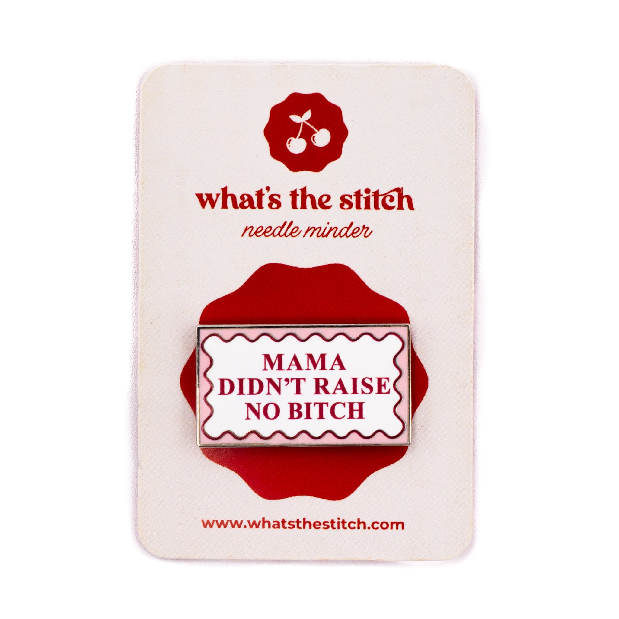 A rectangular enamel needle minder by what's the stitch, featuring the text "MAMA DIDN'T RAISE NO BITCH" in dark blue inside a white and blue scalloped border, mounted on a white display card with a red logo and accents
