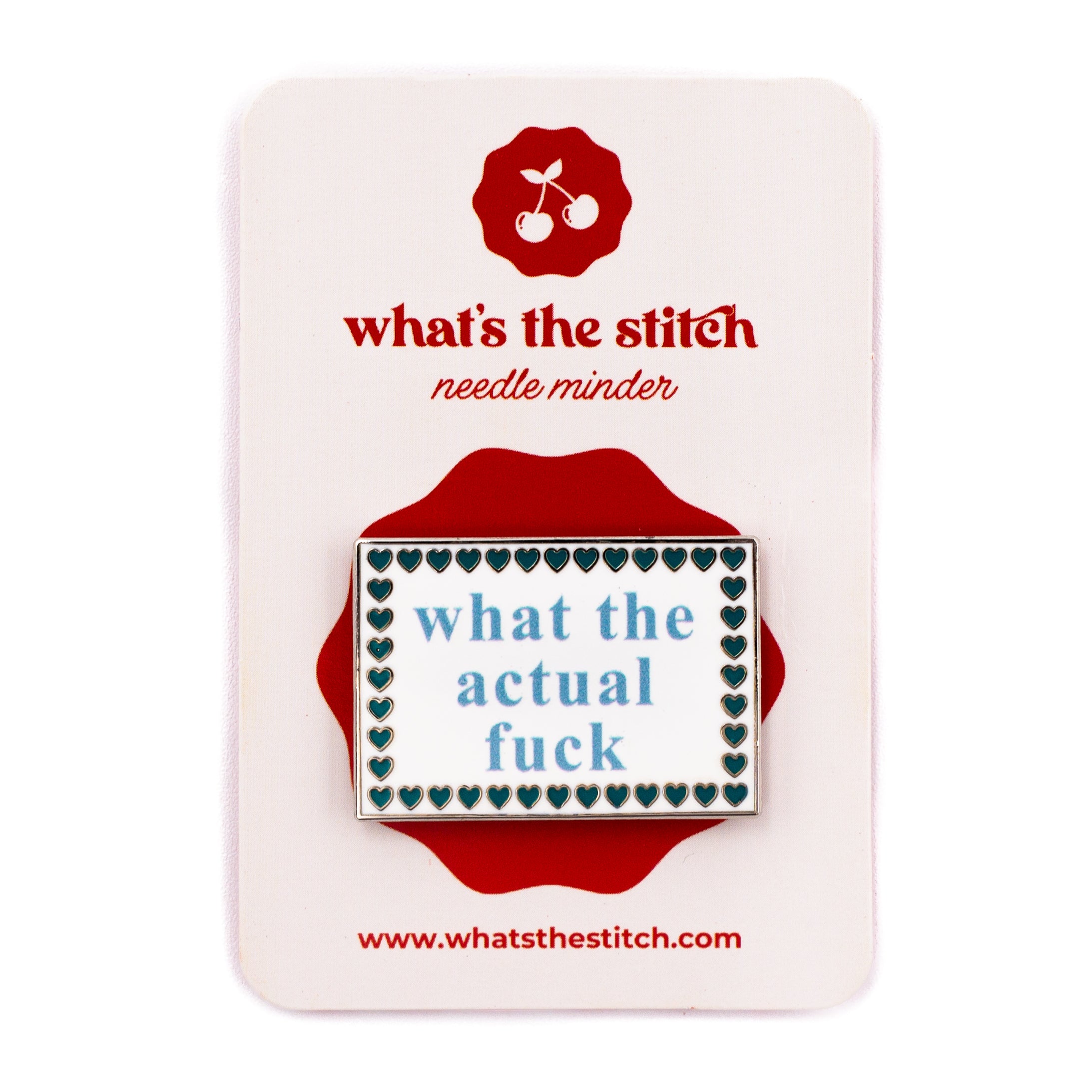 A rectangular enamel needle minder by what's the stitch, featuring the text "WHERE TF IS MY NEEDLE" in dark blue inside a white and blue scalloped border, mounted on a white display card with a red logo and accents