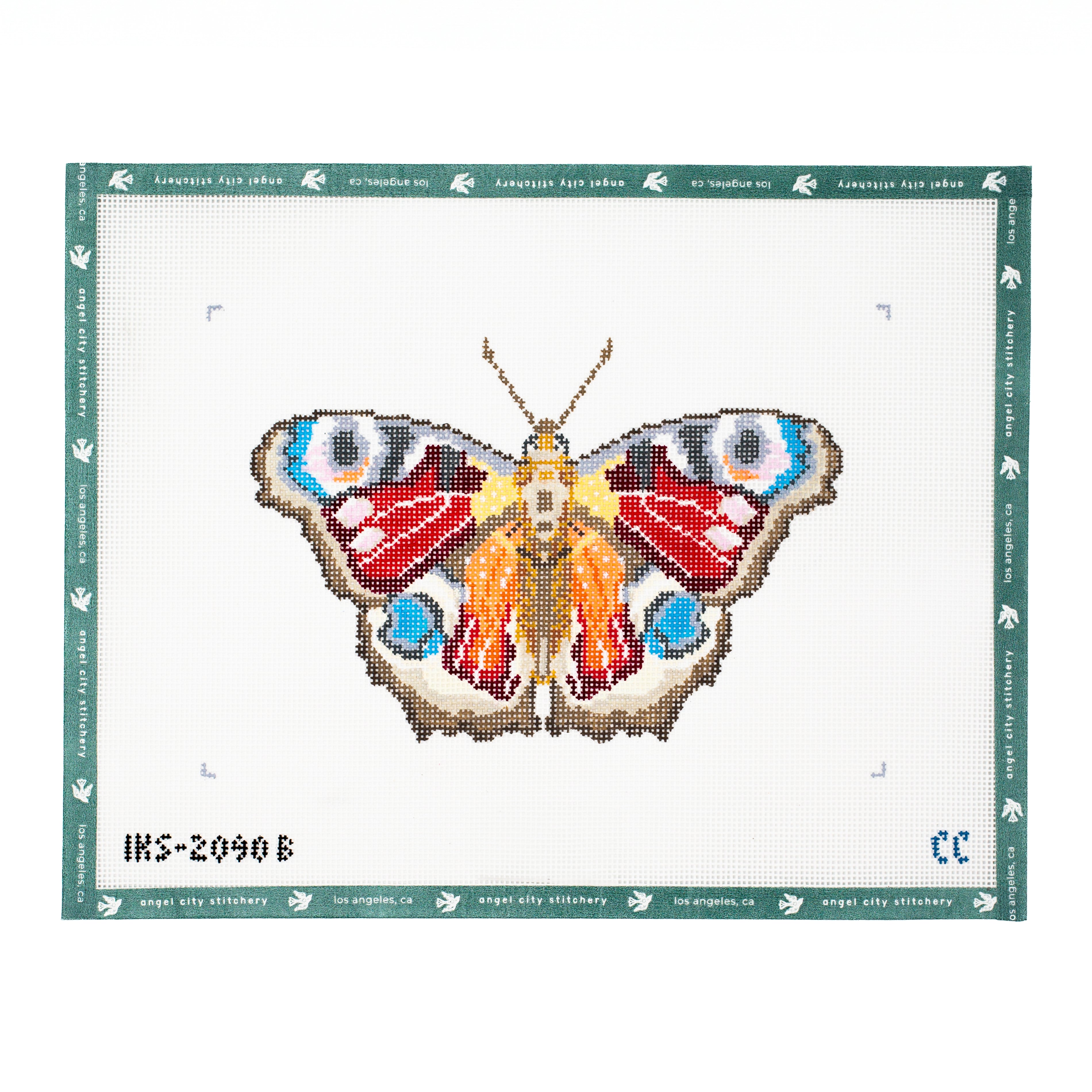 Peacock butterfly needlepoint canvas featuring detailed wings with prominent eyespots in blue, white, and black, rich red and orange patterns, brown borders, a patterned body, and antennae on a white background