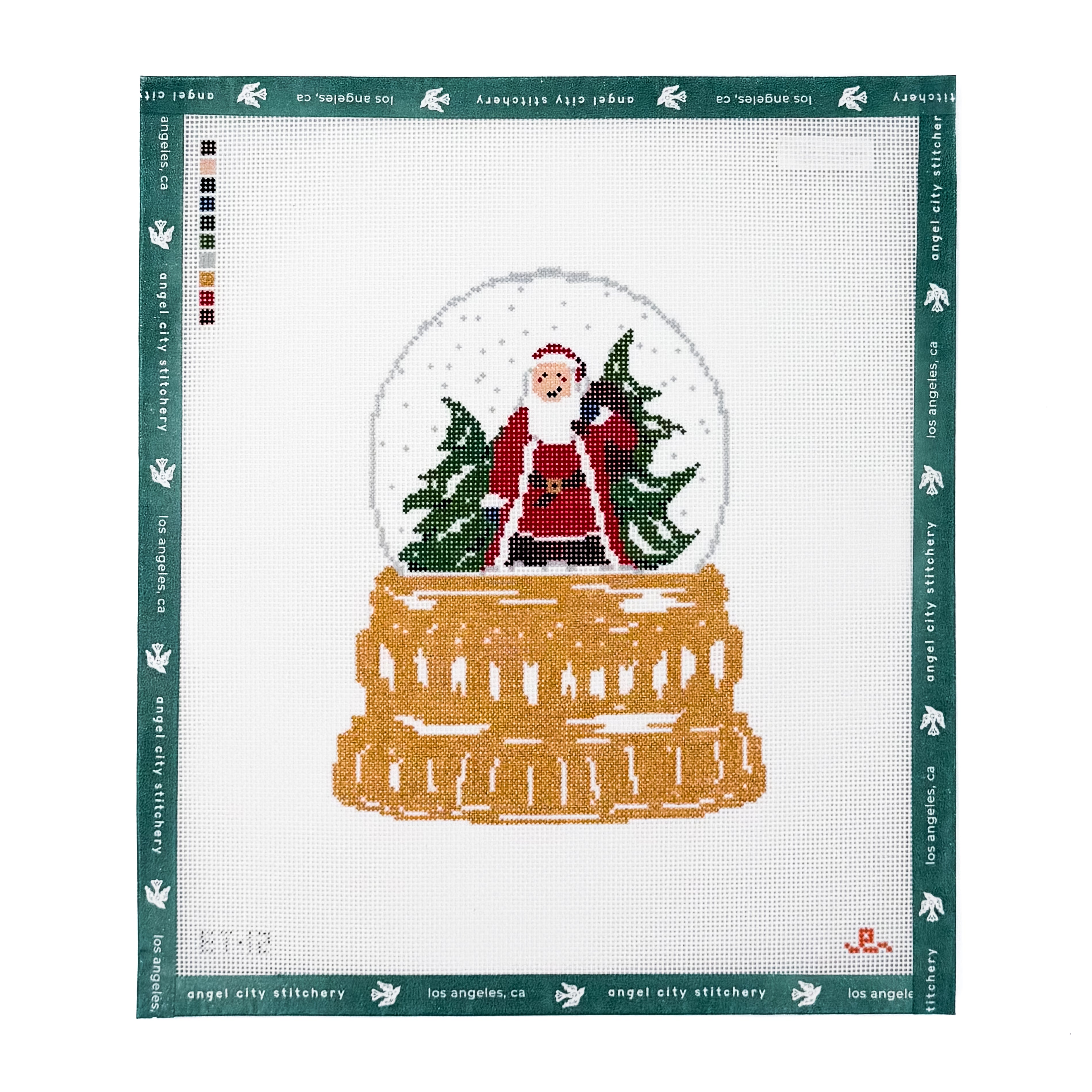 Snow globe needlepoint canvas featuring Santa Claus carrying a Christmas tree amidst falling snow on a golden tiered base