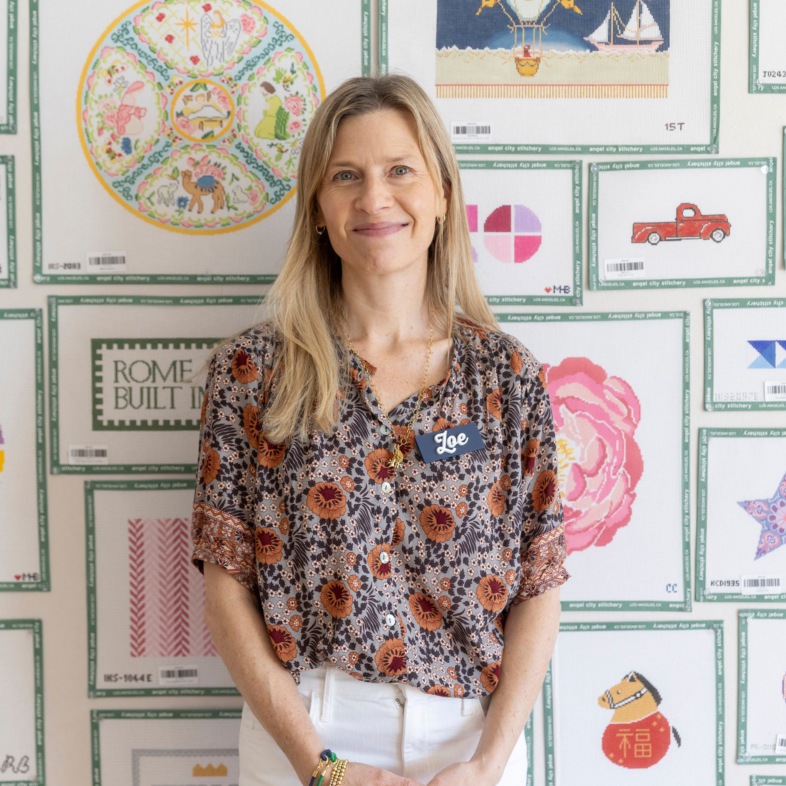 Woman standing in front of a wall with various framed artworks
